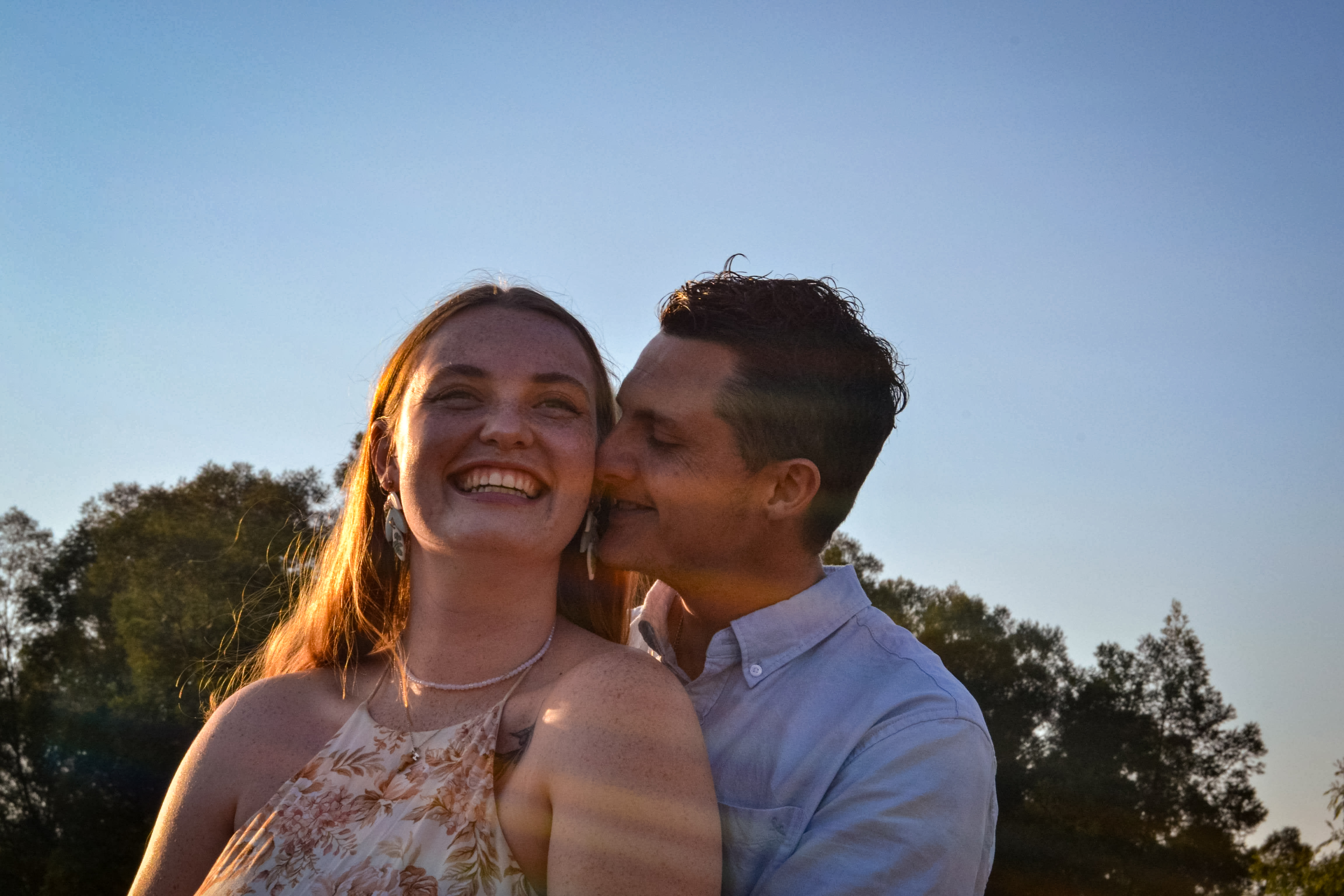 Hannah laughing as Mitchell kisses her cheek